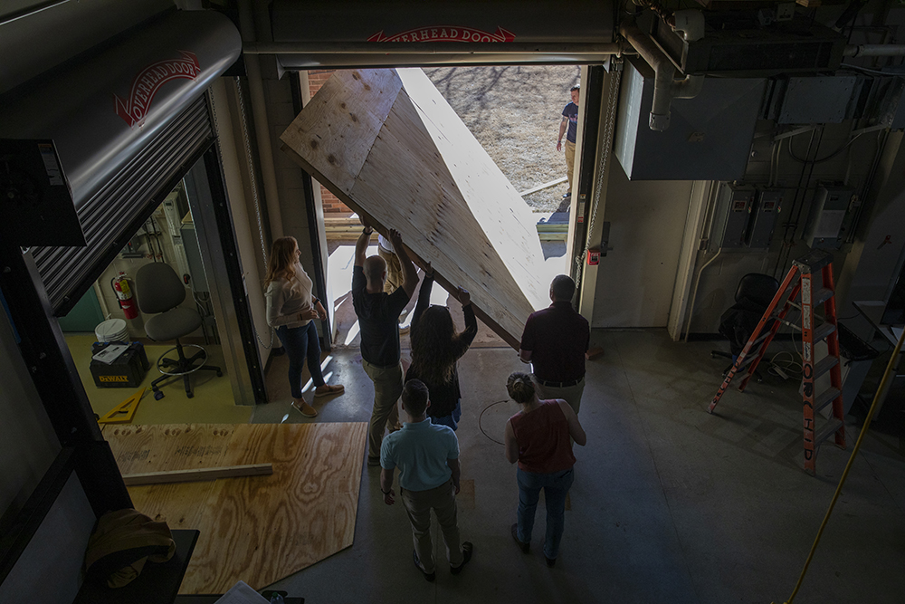 A group of participants carry a piece of wood out of the workshop to work on their decoy. (Credit: Sean McNeil)
