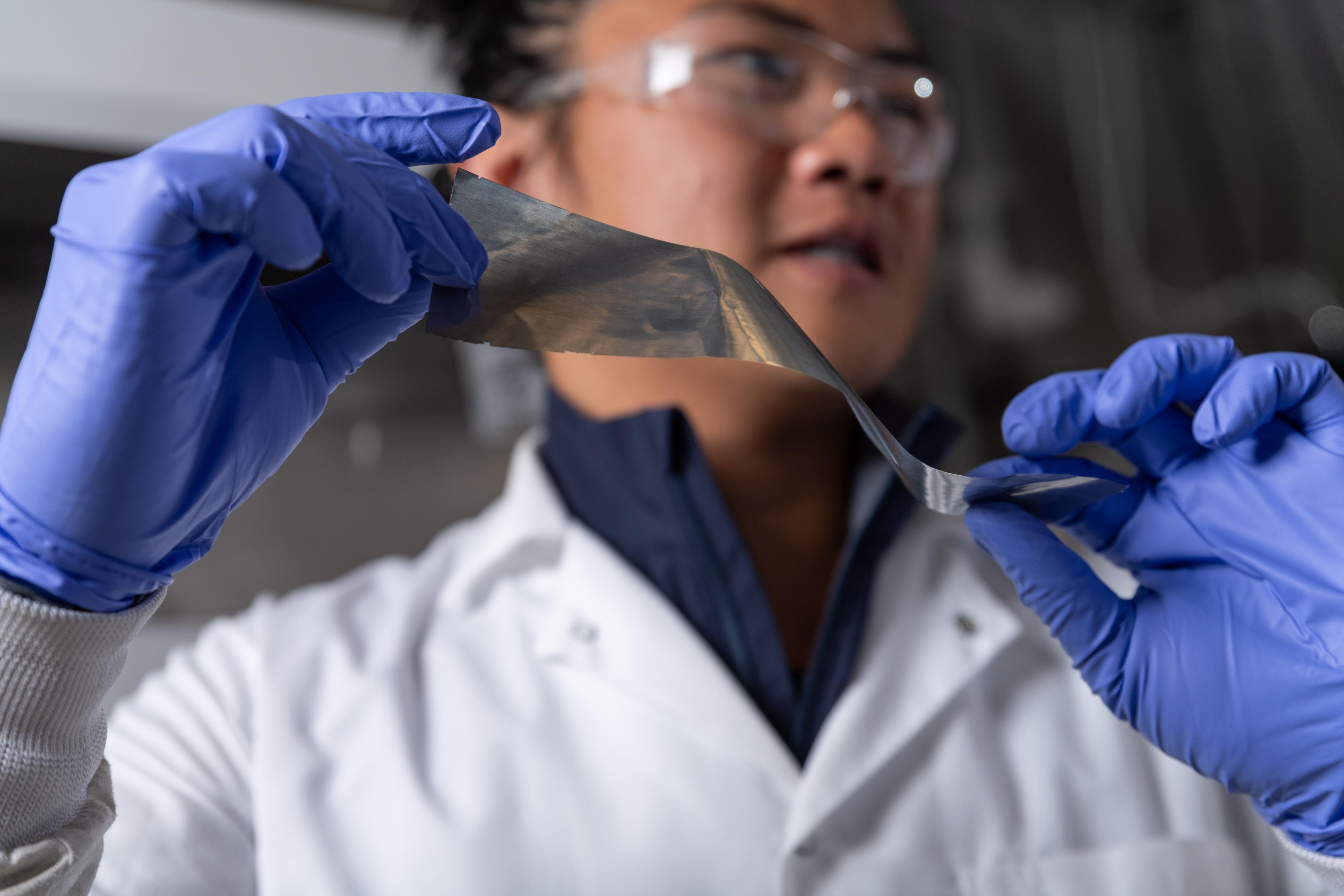 Graduate student researcher Yuhgene Liu holds an aluminum material for solid-state batteries.