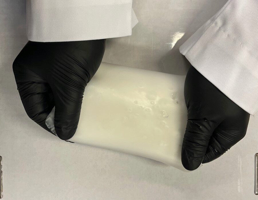 A researcher stretches the large-scale rubber material.