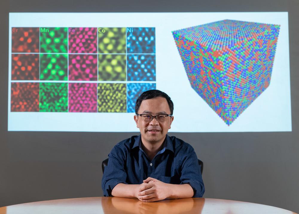 Ting Zhu, professor of mechanical engineering at Georgia Tech, in front of his TEM images of polycrystalline metals and a graphic simulating atomic structure