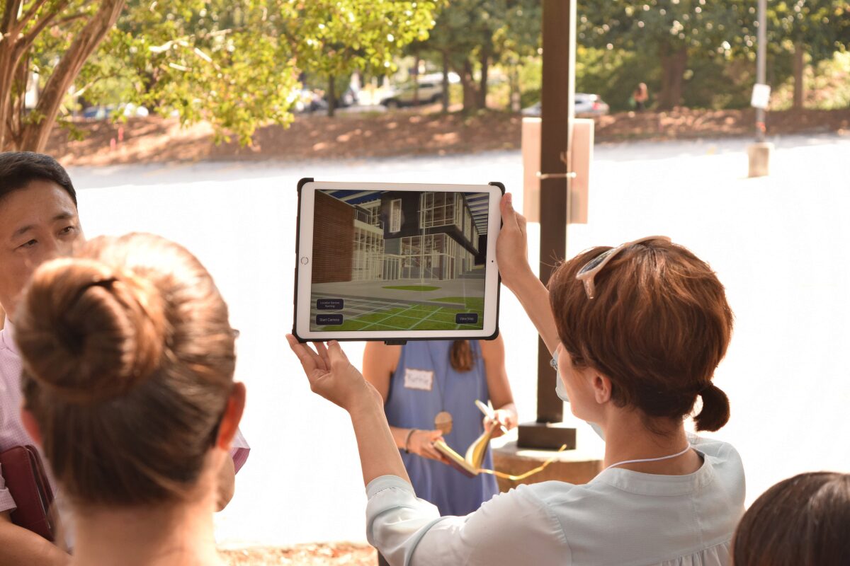 woman holding up display screen as others look on woman holding up display screen as others look on