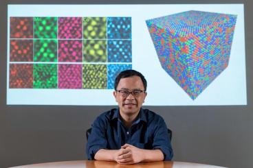 Ting Zhu, professor of mechanical engineering at Georgia Tech, in front of his TEM images of polycrystalline metals and a graphic simulating atomic structure