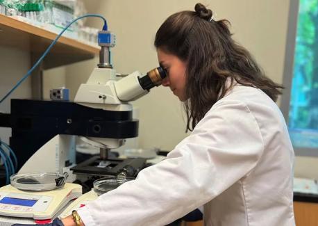 Doctoral student Raphaelle Dodart looks through a microscope at a small sample of clotted blood contained in a microfluidic chip.