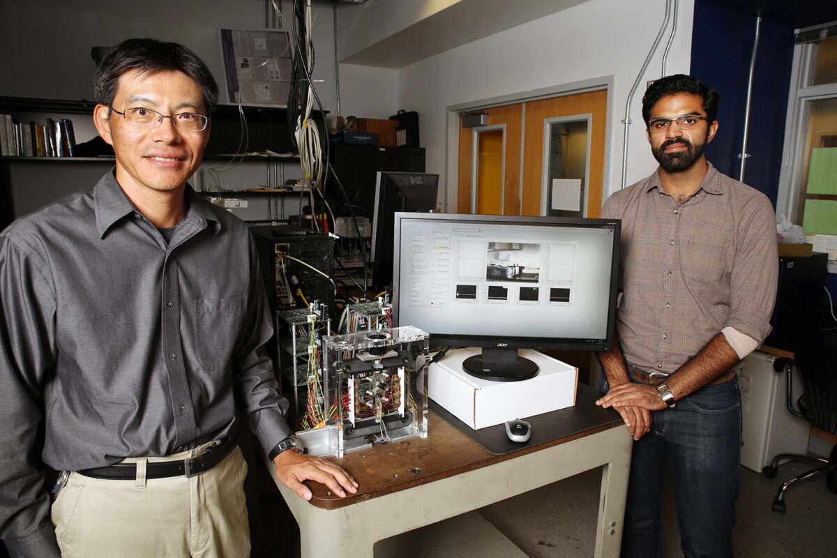 Dr. Ueda standing by table that displays research project Dr. Ueda standing by table that displays research project
