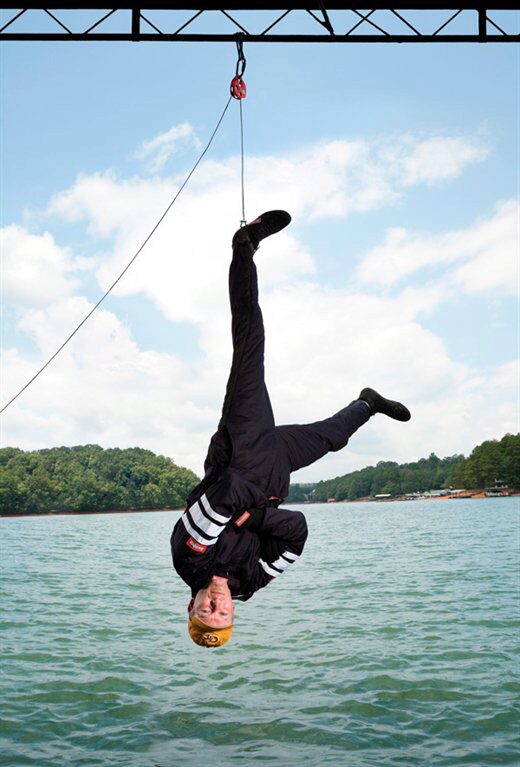 ME alumnus Ian Eyre, stuntman, hanging upside down from structure over water ME alumnus Ian Eyre, stuntman, hanging upside down from structure over water